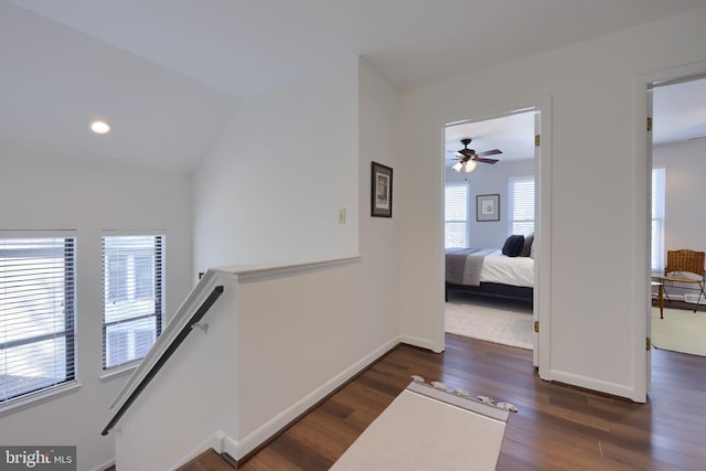 corridor with lofted ceiling, recessed lighting, wood finished floors, an upstairs landing, and baseboards