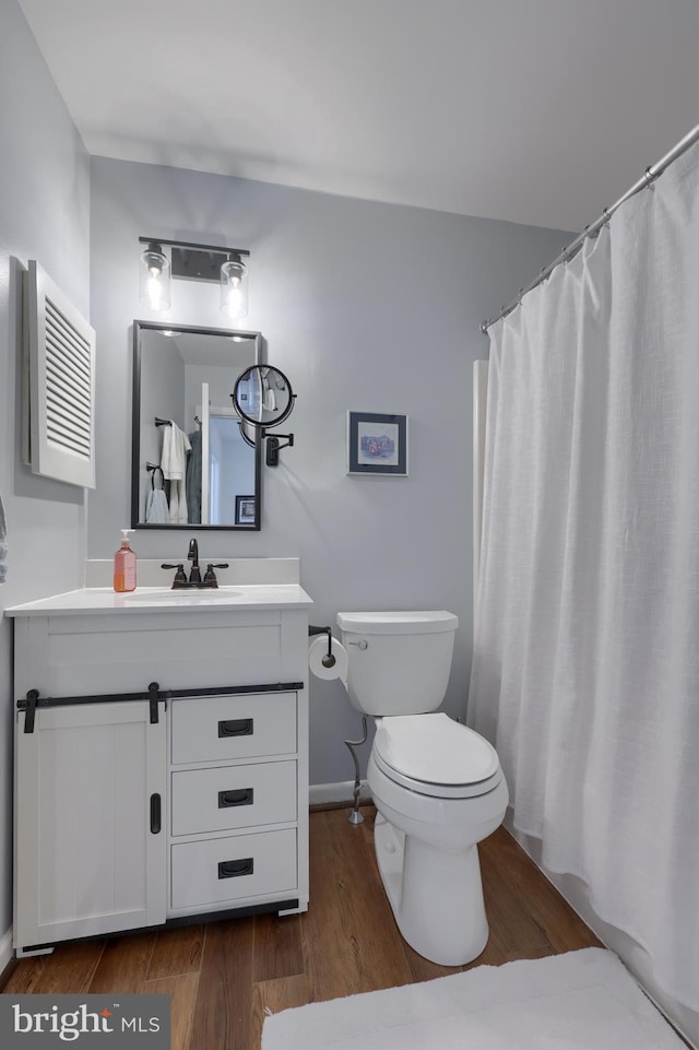 bathroom with toilet, baseboards, wood finished floors, and vanity