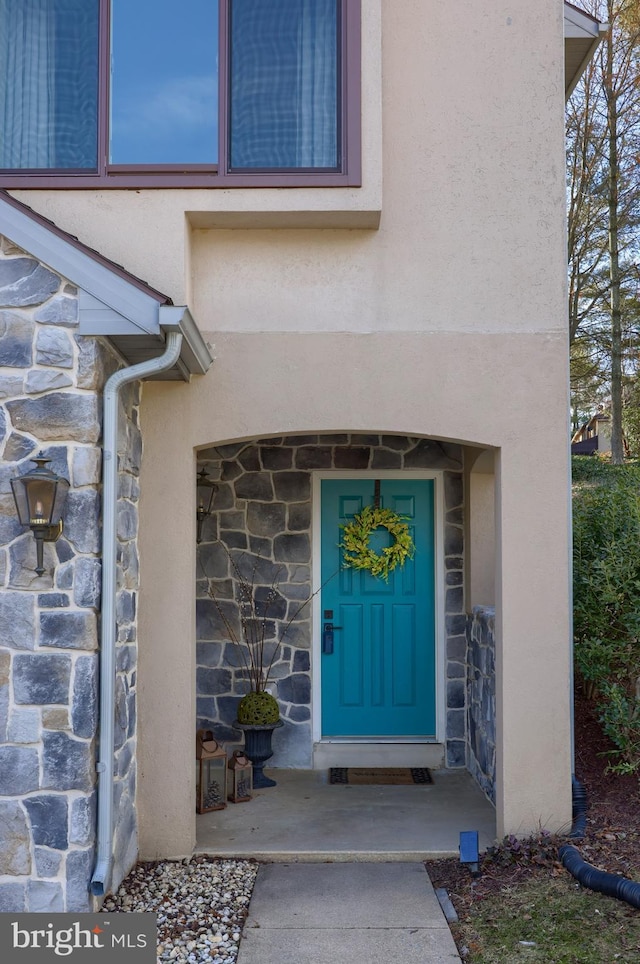 view of exterior entry with stone siding and stucco siding