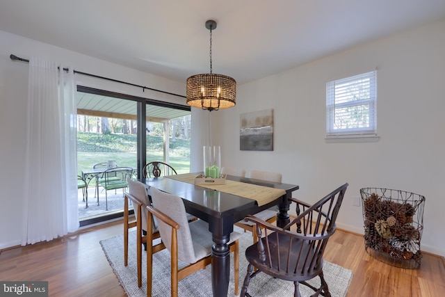 dining area featuring plenty of natural light, light wood finished floors, and an inviting chandelier