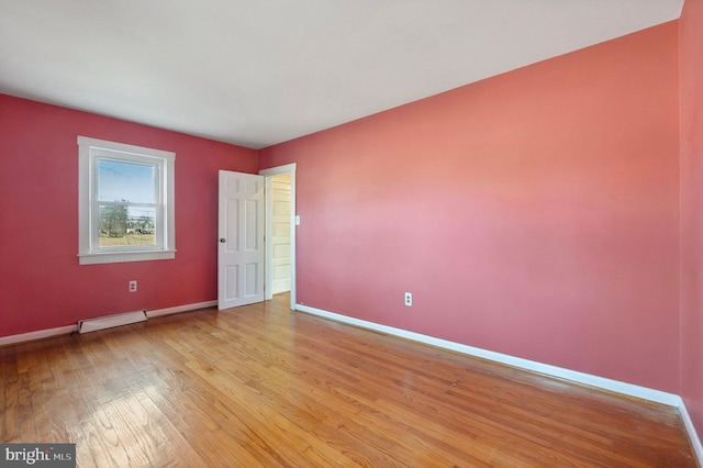 empty room with light wood-style floors, visible vents, and baseboards