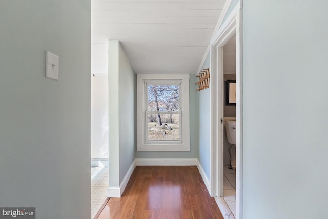 corridor featuring baseboards and wood finished floors