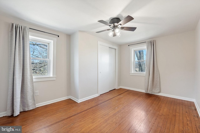 unfurnished bedroom with a ceiling fan, a closet, light wood-style flooring, and baseboards