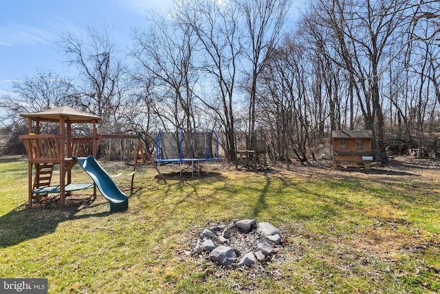 view of yard with a trampoline, an outbuilding, and a playground