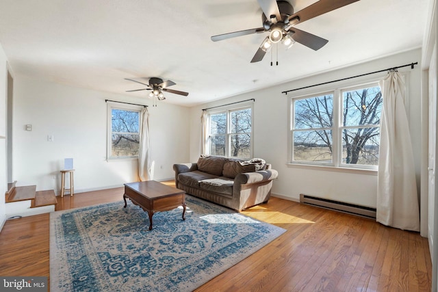 living area with ceiling fan, baseboard heating, wood-type flooring, and baseboards