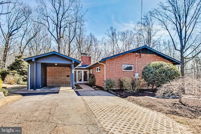 single story home featuring driveway, a chimney, french doors, a carport, and brick siding