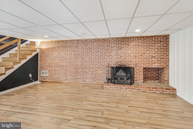 unfurnished living room with stairway, a fireplace, wood finished floors, and visible vents