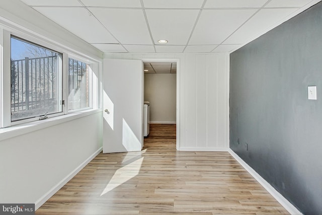 unfurnished room with a paneled ceiling, baseboards, washer and clothes dryer, and light wood finished floors