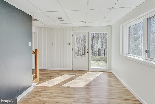 interior space with a wealth of natural light, a paneled ceiling, and wood finished floors