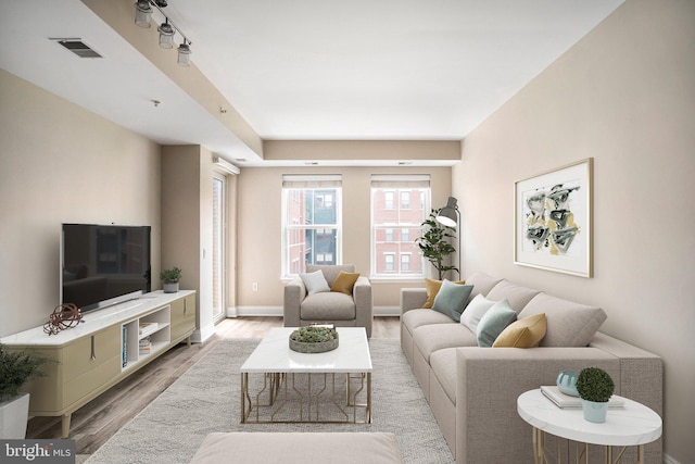 living area featuring visible vents, light wood-style flooring, and baseboards