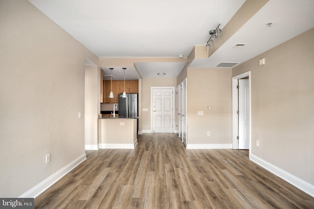 unfurnished living room featuring dark wood-style flooring, visible vents, and baseboards