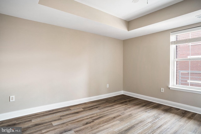 unfurnished room featuring visible vents, baseboards, and wood finished floors