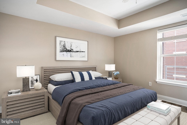 bedroom with visible vents, baseboards, and a tray ceiling