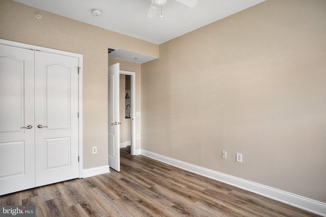 unfurnished bedroom featuring a ceiling fan, a closet, baseboards, and wood finished floors