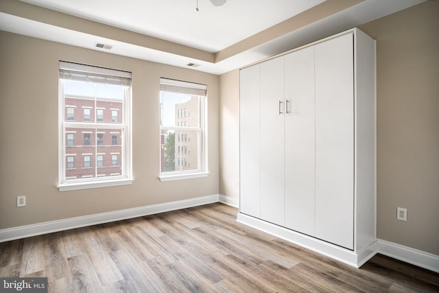 unfurnished bedroom with light wood-style floors, a closet, visible vents, and baseboards