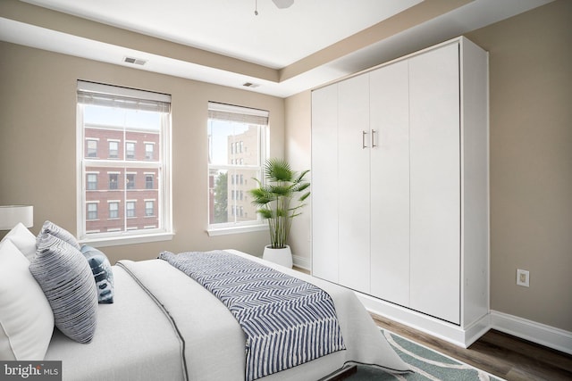 bedroom with dark wood-style floors, visible vents, and baseboards