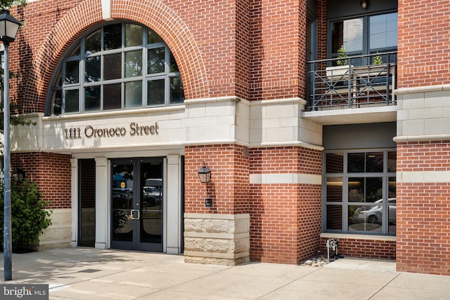 property entrance featuring brick siding, stone siding, and french doors