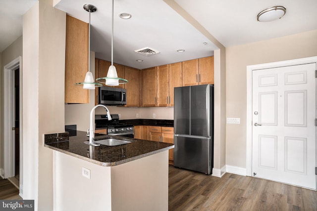 kitchen featuring pendant lighting, visible vents, appliances with stainless steel finishes, dark stone countertops, and a peninsula