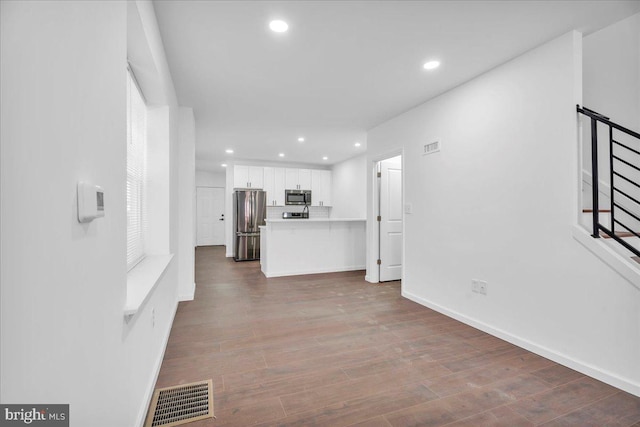 unfurnished living room featuring recessed lighting, wood finished floors, visible vents, baseboards, and stairway