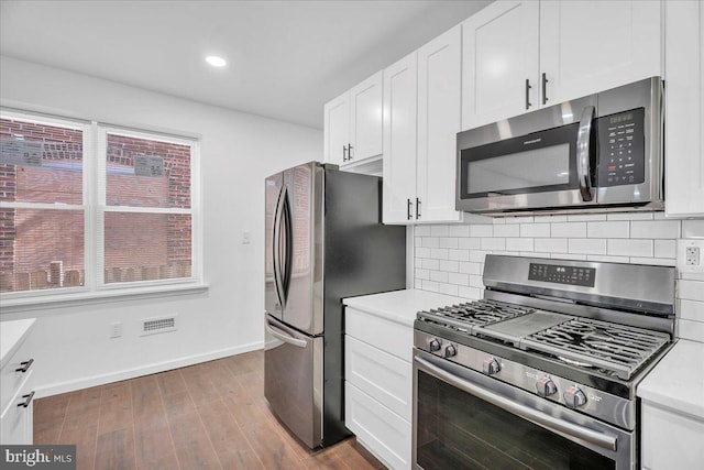 kitchen featuring tasteful backsplash, white cabinetry, appliances with stainless steel finishes, and light countertops