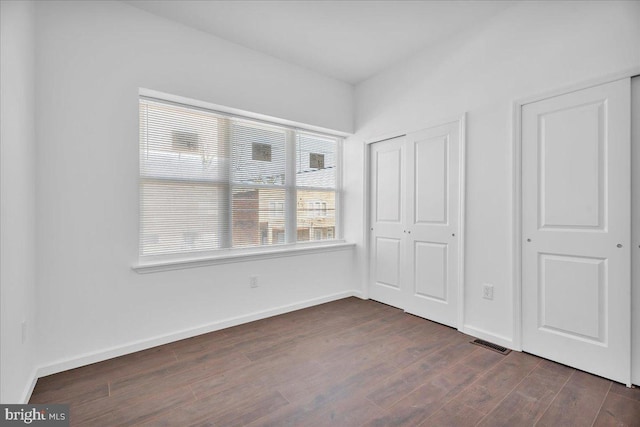 unfurnished bedroom featuring baseboards and dark wood-style flooring