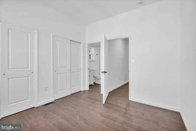 unfurnished bedroom with visible vents, a closet, baseboards, and dark wood-style flooring