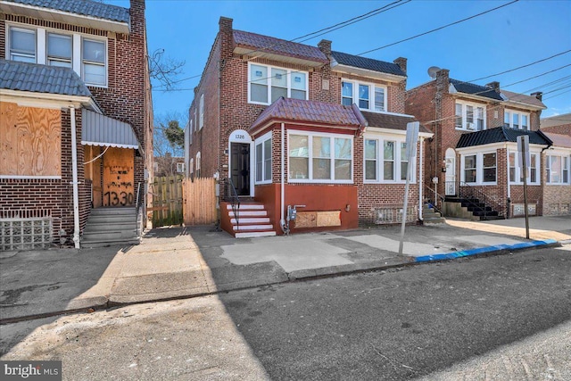 view of front facade featuring brick siding, a tile roof, and fence