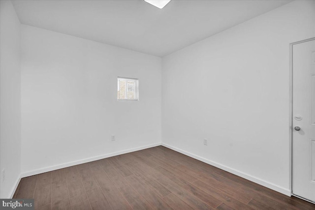 spare room featuring dark wood-style floors and baseboards