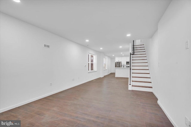 unfurnished living room featuring visible vents, baseboards, dark wood-style floors, stairs, and recessed lighting