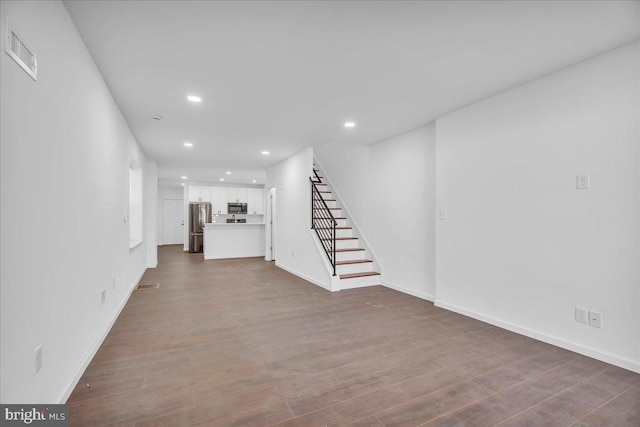 unfurnished living room with dark wood finished floors, recessed lighting, visible vents, baseboards, and stairs