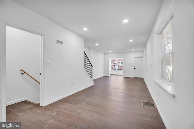 unfurnished living room with dark wood-type flooring, recessed lighting, visible vents, and stairs