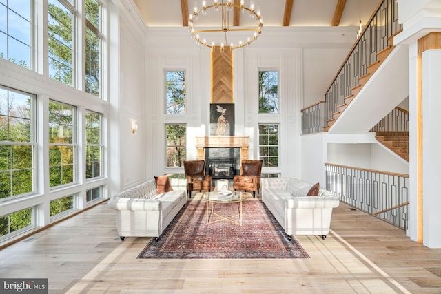 interior space featuring a towering ceiling, beamed ceiling, wood finished floors, stairs, and a notable chandelier