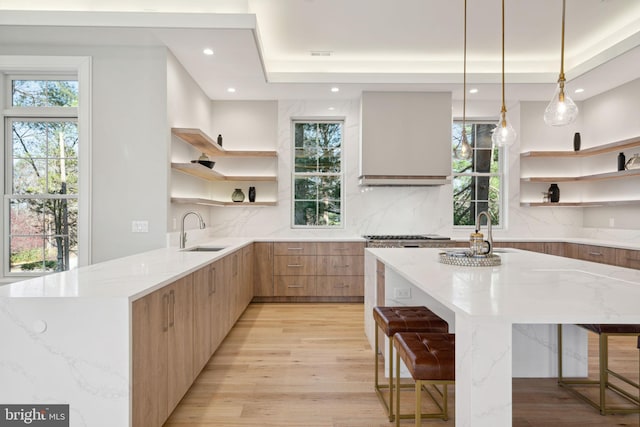 kitchen with light wood finished floors, light stone countertops, open shelves, tasteful backsplash, and modern cabinets