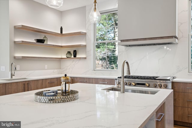 kitchen featuring wall chimney exhaust hood, modern cabinets, brown cabinets, open shelves, and a sink