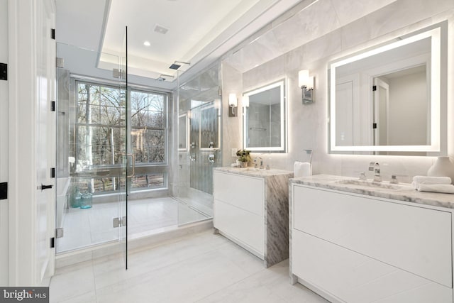 full bath with two vanities, a sink, visible vents, and a shower stall