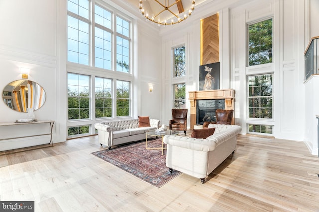 living room featuring a towering ceiling, plenty of natural light, a decorative wall, and a glass covered fireplace