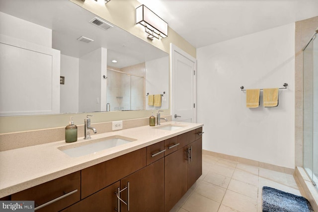 bathroom with double vanity, a shower stall, visible vents, and a sink