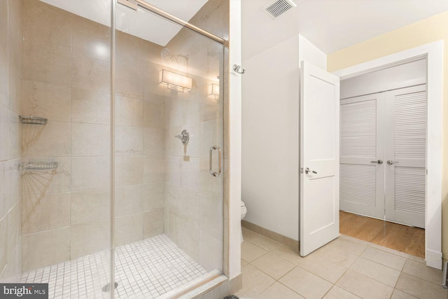 full bathroom featuring toilet, a shower stall, visible vents, and tile patterned floors