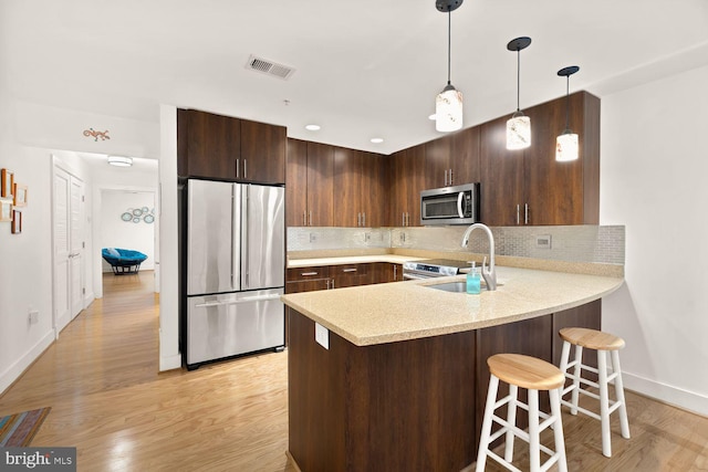 kitchen with light countertops, visible vents, appliances with stainless steel finishes, a sink, and a peninsula