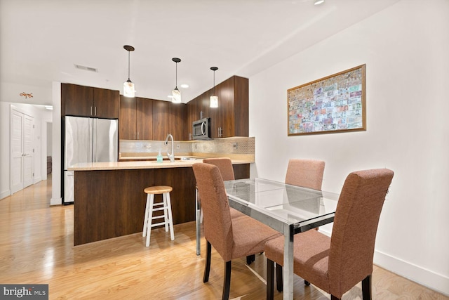 dining space featuring baseboards, visible vents, and light wood finished floors