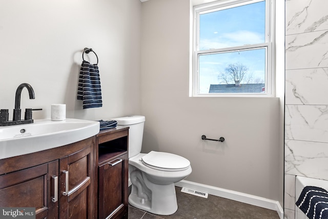 bathroom featuring toilet, vanity, visible vents, and baseboards