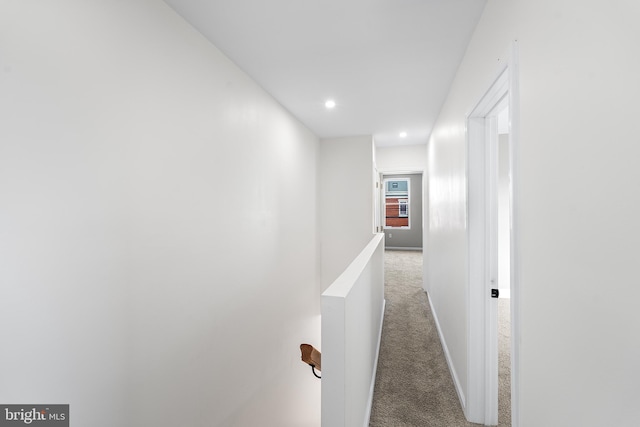 hallway with carpet floors, recessed lighting, baseboards, and an upstairs landing