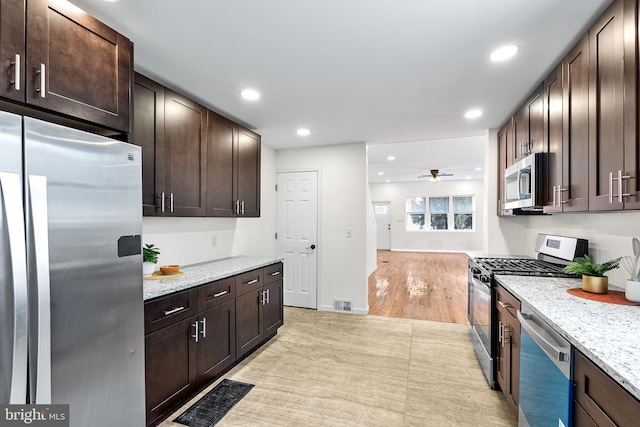 kitchen featuring stainless steel appliances, recessed lighting, dark brown cabinetry, and light stone countertops