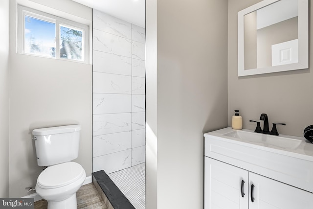 bathroom featuring tiled shower, vanity, toilet, and wood finished floors