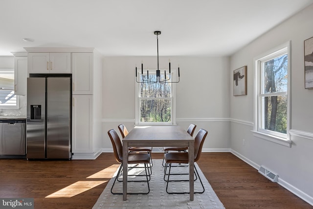 dining area featuring a chandelier, dark wood-type flooring, visible vents, and baseboards