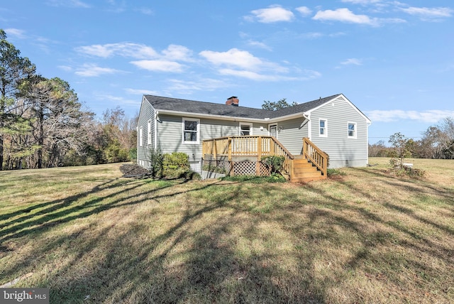 back of property featuring a yard, a chimney, and a wooden deck