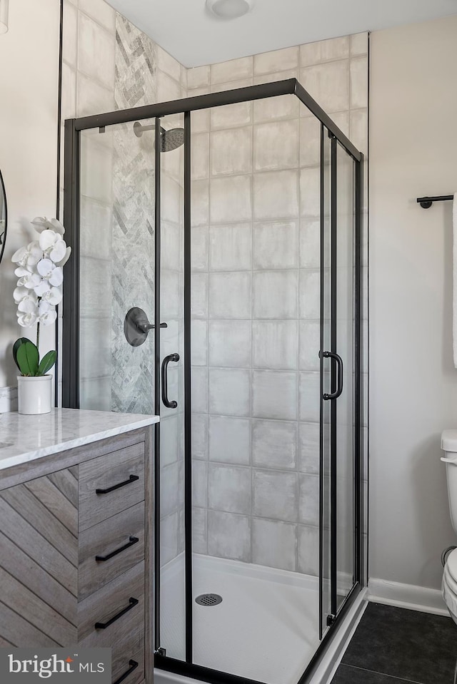 full bath with baseboards, a shower stall, and toilet