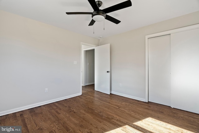 unfurnished bedroom featuring a closet, dark wood finished floors, and baseboards