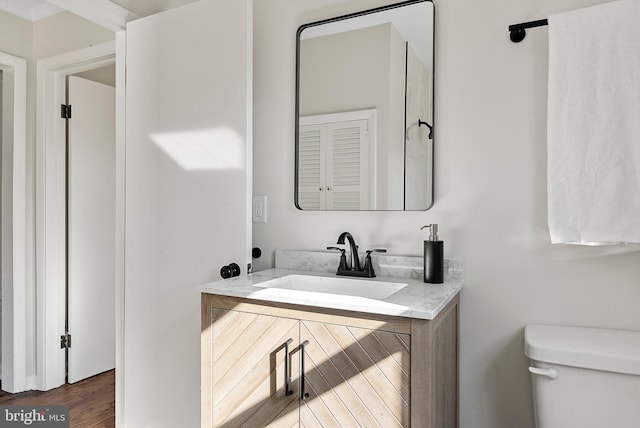 half bathroom featuring toilet, wood finished floors, and vanity