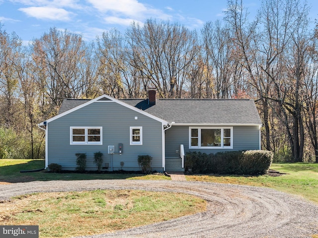 ranch-style house featuring roof with shingles, dirt driveway, a chimney, and a front yard